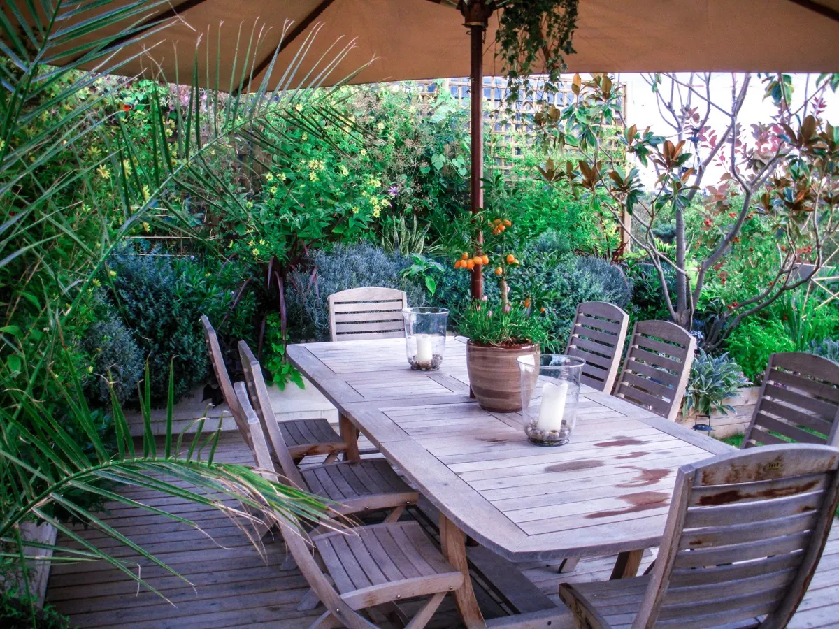 Terrasse de 110 m² à Neuilly-sur-Seine : table de jardin sous parasol entourée de massifs fleuris