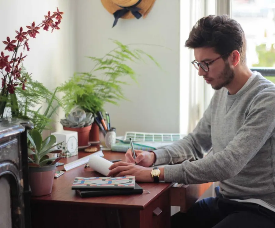 Swandy Wenker, paysagiste à Paris, dessinant un projet de jardin à son bureau parmi ses plantes